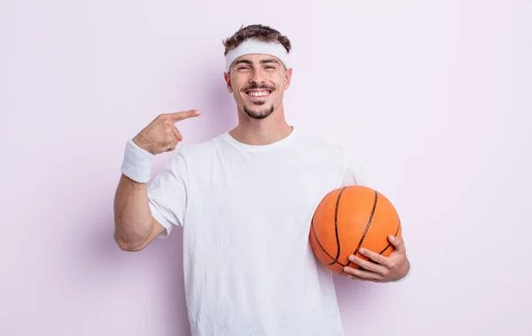 年轻英俊的男人自信地微笑着 指着自己宽阔的笑容 篮球概念 — 图库照片