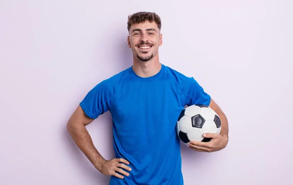 若いハンサムな男が喜んで笑顔で手を腰と自信を持って サッカーのコンセプト — ストック写真