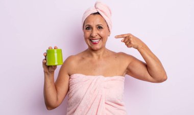 Güzel, orta yaşlı bir kadın kendi gülüşünü işaret ederek gülümsüyor. duş ve saç ürünü konsepti