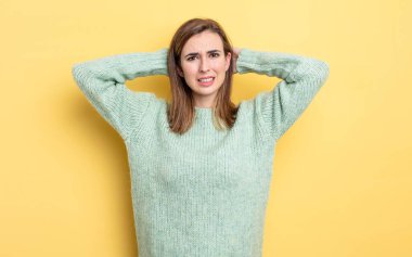 Genç, güzel bir kız kendini stresli, endişeli, endişeli ya da korkmuş hissediyor. Elleri başının üstünde, hatayla panikliyor.