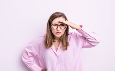 Genç ve güzel kız şaşkınlık ve şaşkınlık içinde bakıyor, el üstünde, uzaklara bakıyor, izliyor ya da arıyor.