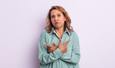 Orta yaşlı kadın şaşkın ve şaşkın görünüyor, güvensiz ve şüpheyle zıt yönleri işaret ediyor.