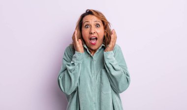 Orta yaşlı bir kadın beklenmedik bir sürpriz yüzünden şaşkın, heyecanlı, gülen, şaşkın ve mutlu hissediyor.