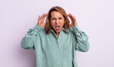Panik içinde bağıran orta yaşlı bir kadın, şok olmuş, korkmuş ya da öfkeli, elleri başının yanında.