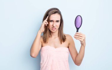 Genç ve güzel bir kadın kafası karışık ve şaşkın hissediyor, deli olduğunu gösteriyor. saç fırçası konsepti