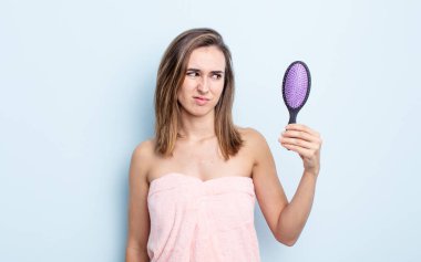 Genç, güzel bir kadın üzgün, üzgün ya da kızgın hissediyor ve yan tarafa bakıyor. saç fırçası konsepti