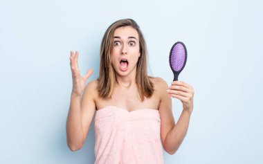 Genç ve güzel bir kadın ellerini havaya kaldırarak çığlık atıyor. saç fırçası konsepti