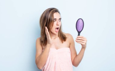 Genç ve güzel bir kadın kendini mutlu, heyecanlı ve şaşırmış hissediyor. saç fırçası konsepti