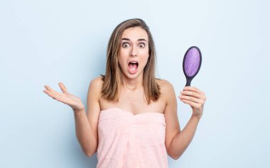 Genç ve güzel bir kadın şok olmuş ve şaşırmış hissediyor. saç fırçası konsepti