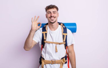 Genç yakışıklı adam kendini mutlu hissediyor, iyi bir jestle onaylıyor. Yürüyüş konsepti