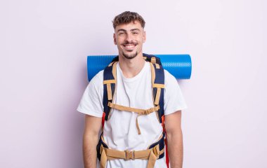 Genç yakışıklı adam mutlu ve hoş bir şekilde şaşırmış görünüyor. Yürüyüş konsepti