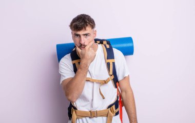 Ağzı ve gözleri açık ve eli çenesinde genç yakışıklı bir adam. Yürüyüş konsepti