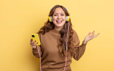 İspanyol güzel kadın kendini mutlu hissediyor, bir çözüm ya da fikir bulduğuna şaşırıyor. kulaklıklar ve akıllı telefon konsepti