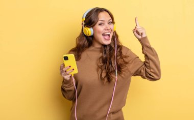 İspanyol güzel kadın bir fikri fark ettikten sonra mutlu ve heyecanlı bir dahi gibi hissediyor. kulaklıklar ve akıllı telefon konsepti