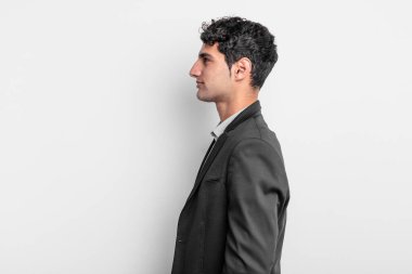 Profil görünümündeki genç işadamı ilerideki boşluğu kopyalamaya çalışıyor, düşünüyor, hayal ediyor ya da hayal kuruyor.