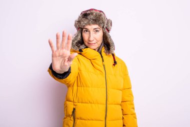 Kıdemli güzel kadın ciddi görünüyor. Avuç içini gösteriyor. Durdurma hareketi yapıyor. kış konsepti