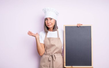 Kıdemli güzel kadın şaşkın, şaşkın ve şüpheci hissediyor. Şef ve karatahta kavramı