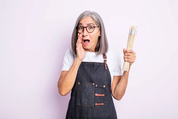 Mulher Bonita Sênior Sentindo Chocado Assustado Artista Com Pincéis — Fotografia de Stock