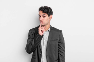 Genç işadamı sessizlik ve sessizlik istiyor, parmaklarıyla ağzının önünde işaret ediyor, 