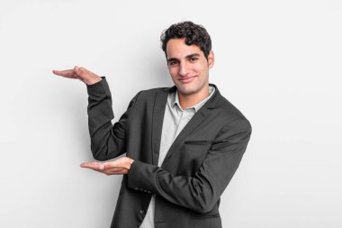 Genç işadamı, iki eli de kenarda olan bir objeyi tutuyor. Kopyalama alanı, bir nesneyi gösteriyor, sunuyor ya da reklamını yapıyor.