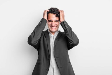 Genç işadamı stresli ve endişeli, depresif ve hayal kırıklığına uğramış hissediyor, iki elini de başa kaldırıyor.