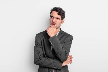 Genç işadamı düşünüyor, kuşkulu ve şaşkın hissediyor, farklı seçeneklerle, hangi kararı vereceğini merak ediyor.