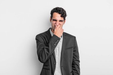 Genç işadamı iğreniyor, pis ve nahoş bir kokuyu koklamamak için burnunu tutuyor.