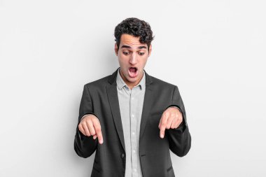 Genç işadamı şok olmuş, ağzı açık ve şaşırmış hissediyor. İnançsızlık ve şaşkınlık içinde bakıyor ve onu işaret ediyor.