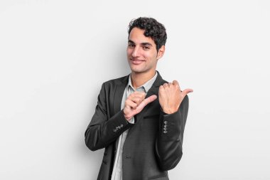 Genç işadamı neşeli bir şekilde gülümsüyor ve yan taraftaki fotokopi alanını işaret ediyor, mutlu ve tatmin olmuş hissediyor.