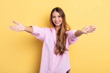 Asyalı güzel kadın neşeyle gülümsüyor sıcak, dostça, sevgi dolu bir kucaklama veriyor, mutlu ve sevimli hissediyor.