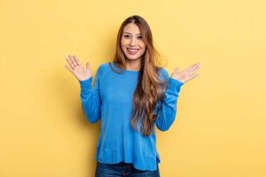 Asyalı güzel kadın mutlu ve heyecanlı görünüyor. Beklenmedik bir sürprizle şoke oldu. İki eli de açık.