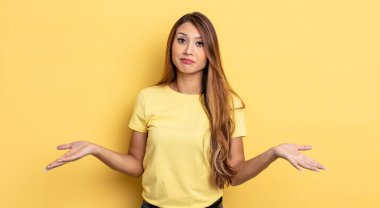 Asyalı güzel kadın şaşkın ve şaşkın hissediyor, doğru cevap veya karardan emin değil, bir seçim yapmaya çalışıyor.