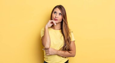 Asyalı güzel kadın düşünceli, meraklı ya da hayal kuruyor, hayal kuruyor ve uzayı kopyalamak için yukarı bakıyor.