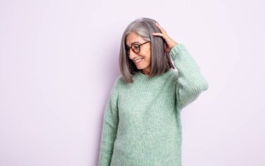 Kıdemli güzel kadın neşeli ve sıradan bir şekilde gülümsüyor, olumlu, mutlu ve kendinden emin bir bakışla yumruk yumruğa.