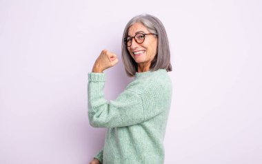 senior pretty woman feeling happy, satisfied and powerful, flexing fit and muscular biceps, looking strong after the gym clipart