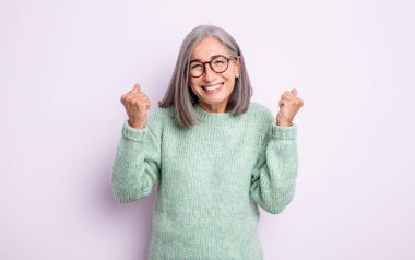 Yaşlı, güzel bir kadın sinirli bir ifadeyle ya da yumruklarıyla başarıyı kutlarken agresif bir şekilde bağırıyor.