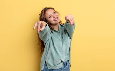 İspanyol güzel kadın mutlu ve kendinden emin, kamerayı iki eliyle gösteriyor ve gülüyor, seni seçiyor.