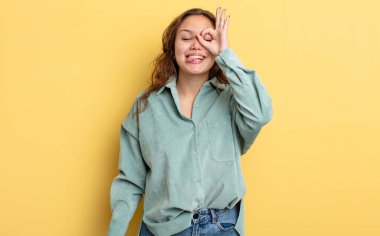 İspanyol güzel kadın mutlu bir şekilde gülümsüyor, şaka yapıyor ve gözetleme deliğinden bakıyor, sırları gözetliyor.