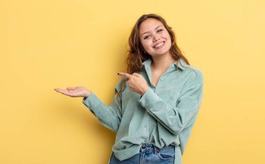 İspanyol güzel kadın gülümsüyor, mutlu, kaygısız ve tatmin olmuş hissediyor, fotokopi alanındaki konsepte ya da fikre işaret ediyor.