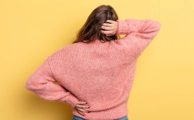 Hispanik güzel kadın düşünüyor ya da şüphe ediyor, kafasını kaşıyor, şaşkın ve şaşkın hissediyor, arkaya ya da arkaya bakıyor.