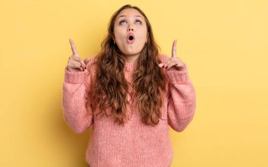 İspanyol güzel kadın şaşırmış, şaşırmış ve ağzı açık görünüyor, iki eliyle boşluğu kopyalamak için yukarı bakıyor.