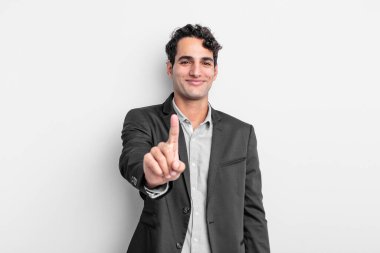 Genç işadamı gururla gülümsüyor ve gururla bir numaralı pozunu veriyor, kendini lider gibi hissediyor.