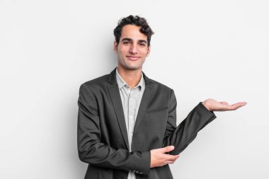 Genç işadamı gururla ve güvenle gülümsüyor, mutlu ve tatmin olmuş hissediyor ve fotokopi alanında bir konsept gösteriyor.