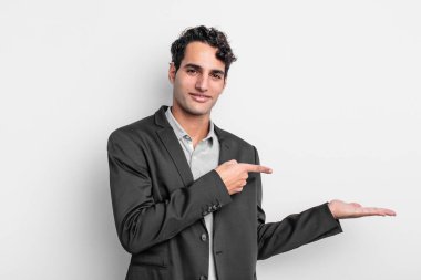 Genç işadamı gülümsüyor, mutlu, kaygısız ve tatmin olmuş hissediyor, fotokopi alanındaki konsepte veya fikre işaret ediyor.