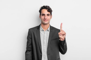 Genç işadamı gülümsüyor ve arkadaş canlısı görünüyor, bir numara veya ilk eli önde, geriye doğru sayıyor.