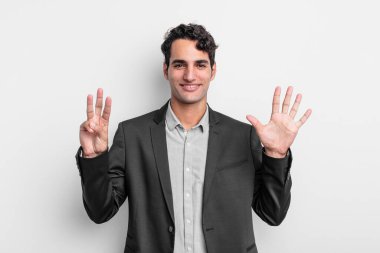 Genç işadamı gülümsüyor ve arkadaş canlısı görünüyor. 8 ya da 8 numarayı gösteriyor.