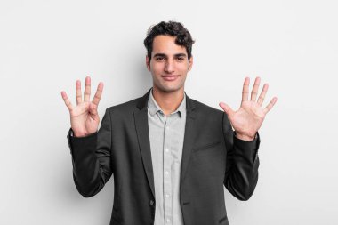 Genç işadamı gülümsüyor ve dost canlısı görünüyor. 9 ya da 9 numarayı gösteriyor. Elleri önde ve geri sayıyor.