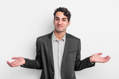 young businessman feeling clueless and confused, having no idea, absolutely puzzled with a dumb or foolish look