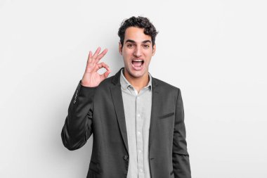 Genç işadamı kendini başarılı ve tatmin olmuş hissediyor, ağzı açık gülümsüyor, elle imza atıyor.