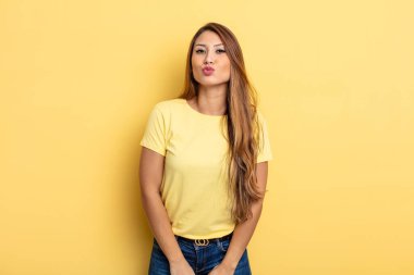 Asyalı güzel bir kadın tatlı, eğlenceli, mutlu, sevimli bir yüz ifadesiyle dudaklarını birbirine bastırıyor.